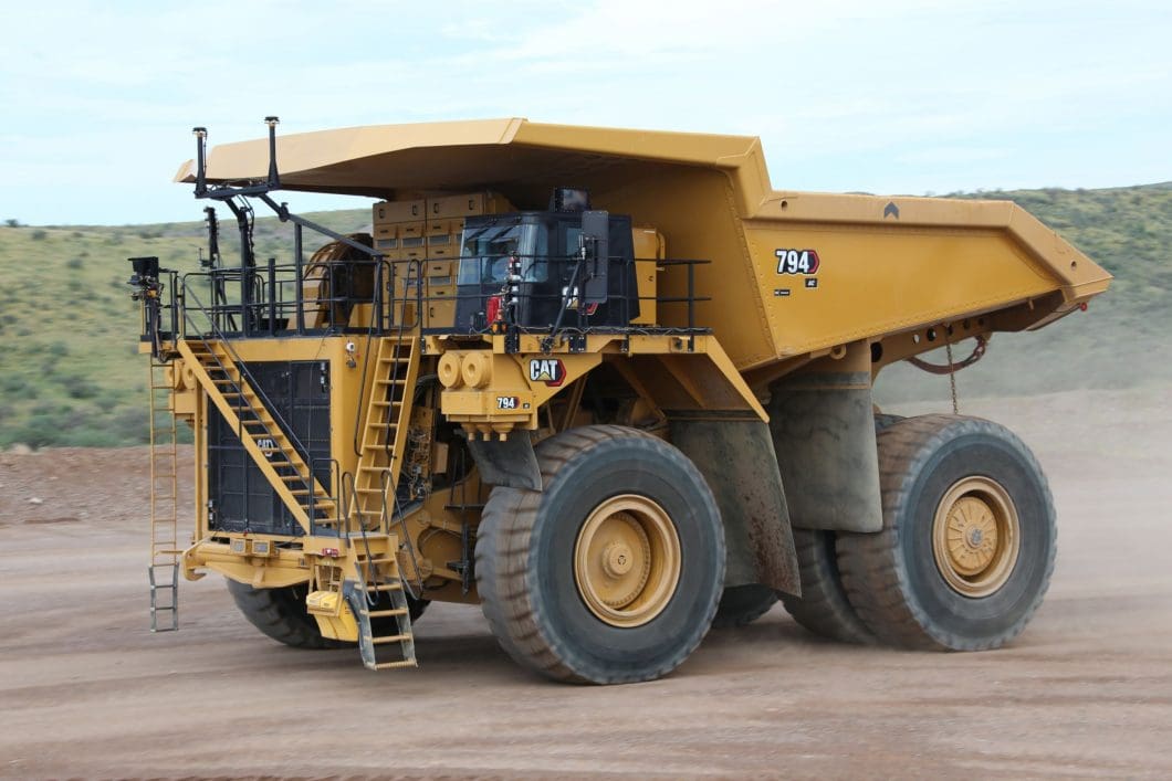 An image of the CAT 749 autonomous mining haulage truck. It appears much like a conventional haulage truck, with the exception of having no cabin for a human operator.