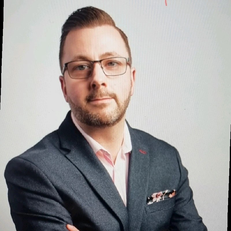 Professional businessman in suit with glasses, confident pose, white background.